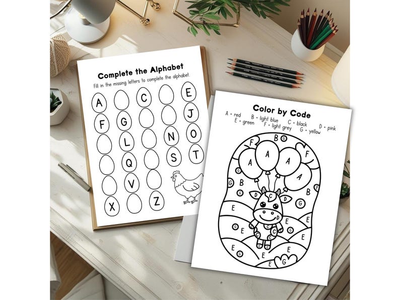 May include: Two activity sheets for children. One sheet is titled "Complete the Alphabet" and features letter blanks. The other sheet is titled "Color by Code" and has a cow graphic with balloons. Pencils and other desk items are in the background.
