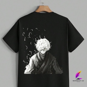 Op de afbeelding: Zwart t-shirt met een grijswaarden anime-stijl illustratie van een personage met wit haar en gele ogen. Het ontwerp bevat een donkere mantel en abstracte vormen. Het shirt hangt aan een houten hanger.