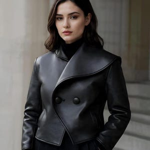May include: A black leather jacket with a unique collar design and two large buttons. The jacket has a tailored fit and a sleek, modern aesthetic. The model is wearing a black turtleneck underneath.