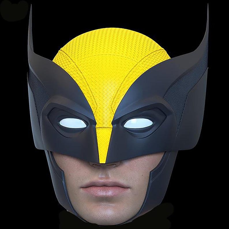 May include: A black and yellow Wolverine mask with white eye lenses. The mask features a textured yellow top and black detailing, including pointed ear-like extensions. The mask is designed to fit over a person's face.