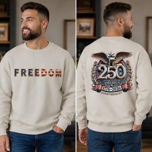 May include: A beige crewneck sweatshirt featuring the word FREEDOM on the front in a red, white, and blue flag pattern. The back displays a graphic with a bald eagle, the number 250, and the text UNITED STATES OF AMERICA 1776-2026 ANNIVERSARY.