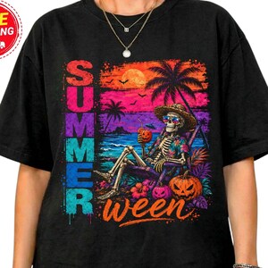 May include: A black short-sleeve t-shirt featuring a graphic of a skeleton wearing a straw hat and sunglasses, sitting in a beach chair. The design includes a sunset, palm trees, a jack-o'-lantern, and the text SUMMERween in colorful letters.