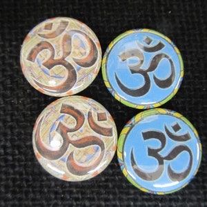 May include: Four round buttons with the Om symbol in different styles. The buttons have a blue, yellow, and brown background with black Om symbols.