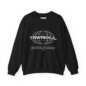 May include: Black crew neck sweatshirt with the word "TAWAKKUL" in white, encircled by a globe design. Below the word is the text: "Plans may break, paths may twist, but the One who holds the outcome never errs."