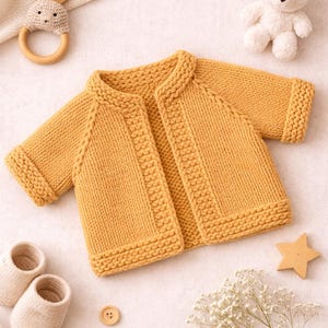 Può includere: Cardigan per neonati lavorato a maglia giallo senape con colletto rotondo e polsini a coste. L'immagine include anche un sonaglio di legno a forma di coniglietto, un orsacchiotto bianco, scarpine e bottoni di legno. Un ritaglio di legno a forma di stella e rametti di fiori bianchi completano la scena.