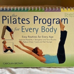 May include: A book titled "The Pilates Program for Every Body" by Carolan Brown. The cover features a woman doing a Pilates exercise and a man doing a Pilates exercise. The book is a Reader's Digest publication.