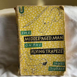 May include: A yellow book cover with a black and white illustration of a man on a trapeze. The title of the book is "The Middle Aged Man on the Flying Trapeze" by James Thurber.