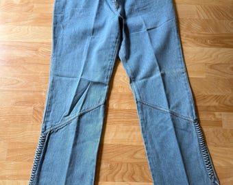 Jeansy vintage z lat 80. i 90. z wysokim stanem i rozszerzanymi nogawkami, zdobione wyjątkowymi, plecionymi akcentami w stylu boho. Wykonane w 100% z bawełny, rozmiar 12 (obwód w pasie 30 cali).