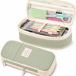 May include: A sage green rectangular pencil case with a zipper closure and a white label reading SPECIAL. The case is shown both closed and open, revealing internal mesh pockets, elastic pen loops, and various stationery items like pens and scissors.