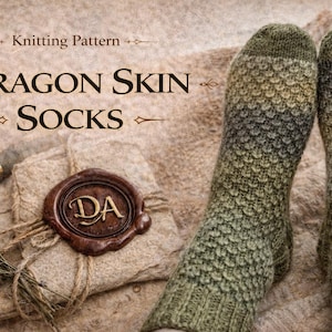 May include: A pair of knitted socks with a dragon scale pattern in shades of green, brown, and gray. The socks are displayed with a bundle of dried flowers, a wax seal, and the text "Dragon Skin Socks".