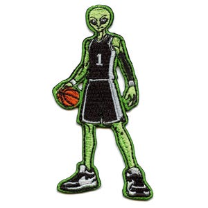May include: Embroidered patch featuring a green alien basketball player wearing a black jersey with the number 1. The alien is holding an orange basketball. The patch has a green border and black and white accents.
