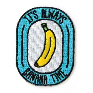 May include: Embroidered patch with a blue border and the text "IT'S ALWAYS BANANA TIME". The patch features a yellow banana with a green stem on a white background. The patch is oval-shaped.