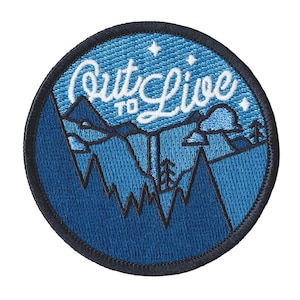 May include: Circular embroidered patch with a blue mountain landscape design. The patch features the text "Out to Live" in white script across the top. The patch has a black border and is suitable for jackets, bags, or other fabric items.