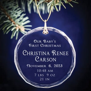 May include: A clear glass Christmas ornament with the text "OUR BABY'S FIRST CHRISTMAS" and the name "CHRISTINA RENEE CARSON". The ornament also includes the date "NOVEMBER 6, 2023", time "10:48 AM", weight "7 LBS 9 OZ", and length "21 IN".