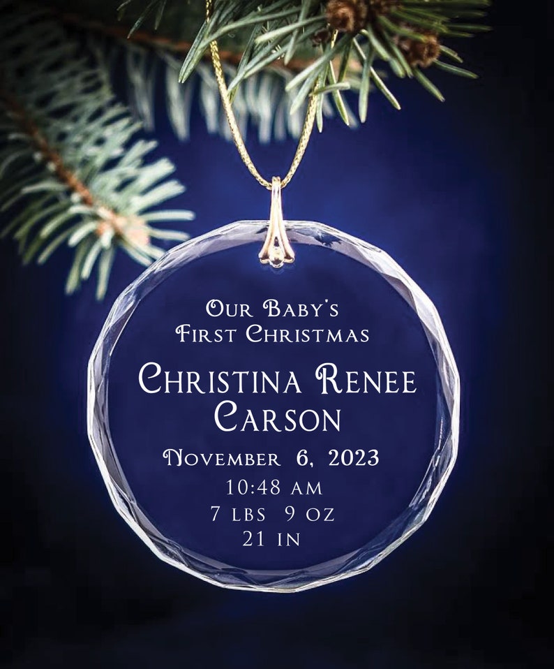 May include: A clear glass Christmas ornament with the text "OUR BABY'S FIRST CHRISTMAS" and the name "CHRISTINA RENEE CARSON". The ornament also includes the date "NOVEMBER 6, 2023", time "10:48 AM", weight "7 LBS 9 OZ", and length "21 IN".