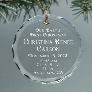 May include: Clear glass Christmas ornament with the text "Our Baby's First Christmas Christina Renee Carson November 6, 2023 10:48 AM 7 LBS 9 OZ 21 IN ANDERSON, CA"