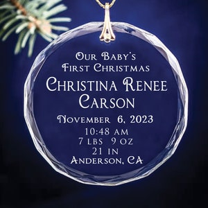 May include: A clear glass Christmas ornament with the text "OUR BABY'S FIRST CHRISTMAS" and the name "CHRISTINA RENEE CARSON". The ornament also includes the date "NOVEMBER 6, 2023", the time "10:48 AM", the weight "7 LBS 9 OZ", the length "21 IN", and the location "ANDERSON, CA".
