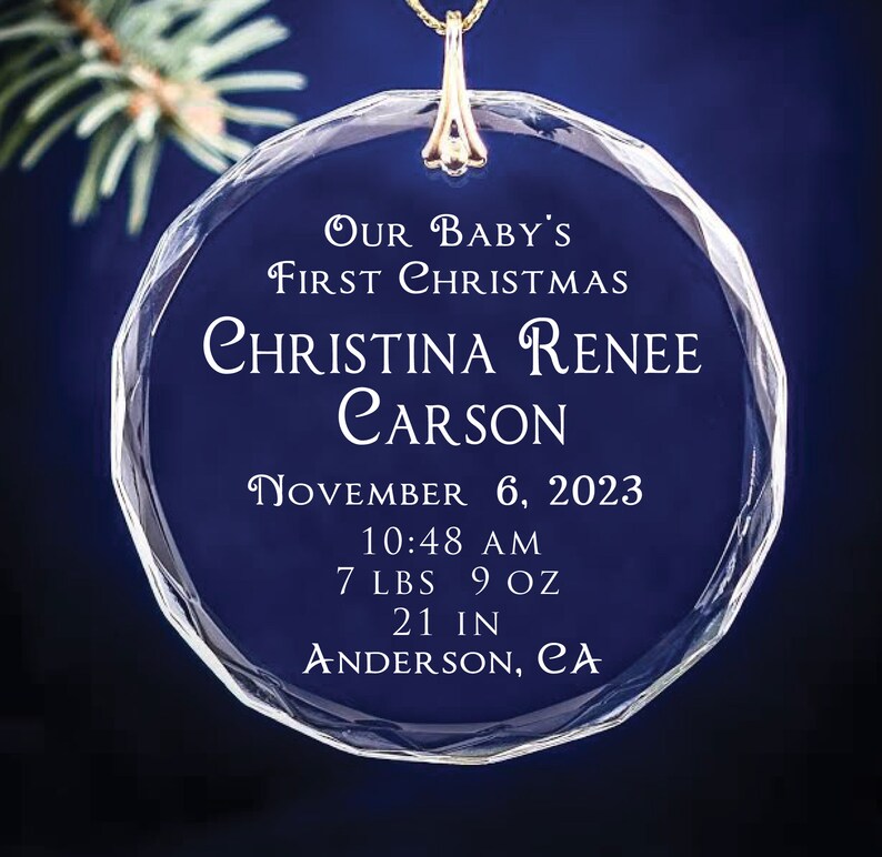 May include: A clear glass Christmas ornament with the text "OUR BABY'S FIRST CHRISTMAS" and the name "CHRISTINA RENEE CARSON". The ornament also includes the date "NOVEMBER 6, 2023", the time "10:48 AM", the weight "7 LBS 9 OZ", the length "21 IN", and the location "ANDERSON, CA".