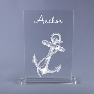 May include: A clear acrylic sign with a white anchor illustration and the word "Anchor" in white cursive lettering.