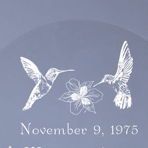 May include: A light blue decorative item with white hummingbird and flower illustrations. The text "November 9, 1975" is also visible. The design features two hummingbirds and a flower.
