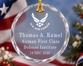May include: A circular clear glass ornament with faceted edges, featuring a gold-toned metal bail. The center displays the U.S. Air Force logo above the text: Thomas A. Kamel, Airman First Class, Defense Institute, 18 DEC 2026.