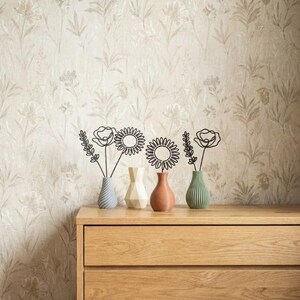 May include: A wooden chest of drawers with two drawers displays four small vases, each holding a wire flower sculpture. The vases are in blue, white, and brown. The background is floral wallpaper.