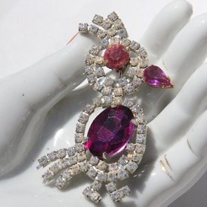 Könnte beinhalten: Eine vintage Brosche aus Strass in Form eines Vogels mit rosa und violetten Steinen.
