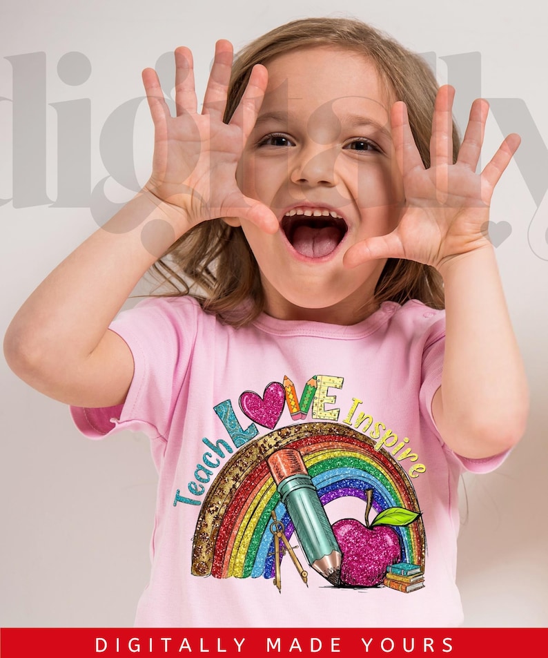 May include: A young person wearing a pink t-shirt with a colorful graphic. The graphic includes a rainbow, pencil, apple, and the words "Teach Love Inspire". The person is smiling and holding their hands up.