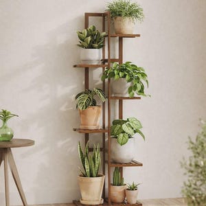 May include: A tall, dark brown wooden plant stand with multiple shelves, displaying various potted plants. The plants include leafy green varieties and succulents in neutral-colored pots. The stand is positioned against a neutral-toned wall.