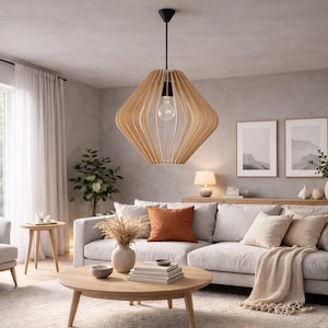May include: A modern living room with a light color palette. A large, light-colored sofa is adorned with pillows and a throw blanket. A wooden, geometric pendant light hangs above a round coffee table. The room features a rug, armchair, and side tables.
