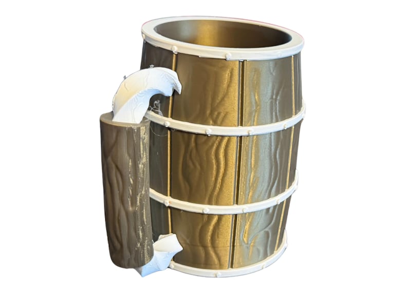 May include: A decorative water fountain with a barrel design. The fountain is gold with white trim and a faux wood grain texture. A small log-shaped element is attached to the side, with water flowing from it.