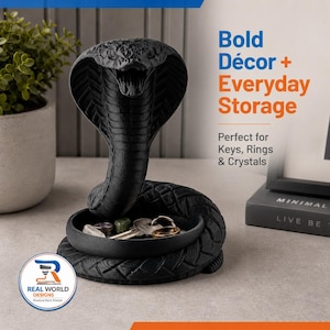 May include: A black cobra-shaped storage dish with the text "Bold Décor + Everyday Storage". The dish holds keys and small crystals. The design is 3D printed and features a detailed snake head.