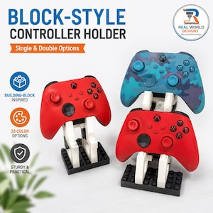 May include: A display of three video game controller holders. Two red controllers are displayed on white and black block-style stands. A blue camouflage controller is displayed on a similar stand. The text on the image says "Block-Style Controller Holder".
