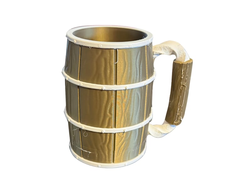 May include: A large, decorative mug with a barrel design. The mug is primarily gold with white accents around the top and the three bands. The handle is a light brown color. The mug is designed to look like a wooden barrel.