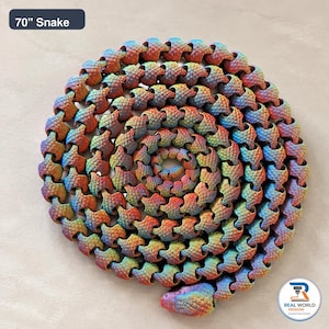May include: A 70" snake toy with a multi-colored gradient finish featuring red, orange, yellow, green, and blue hues. The articulated, segmented body has a textured scale pattern throughout, coiled in a circular shape with a distinct head.