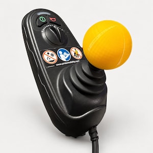 Puede incluir: Un controlador de joystick negro para scooter de movilidad con un mango esférico de color amarillo brillante. El panel de control incluye un botón de encendido, un botón de bocina, un dial de velocidad y una etiqueta con iconos de seguridad.