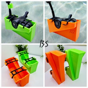 Può includere: Una collezione di dispositivi stampati in 3D in verde brillante e arancione. I dispositivi hanno una struttura a forma di scatola con componenti neri, tra cui ruote e maniglie. Le lettere "BS" sono visibili su alcuni dei dispositivi. I dispositivi sembrano essere progettati per l'uso subacqueo.