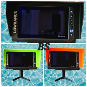 Può includere: Un ecoscandaglio Lowrance Elite nero con visiera protettiva. Lo schermo è scuro e il dispositivo ha pulsanti sul lato destro. Vengono mostrate due unità aggiuntive con visiere verdi e arancioni, montate su supporti neri.