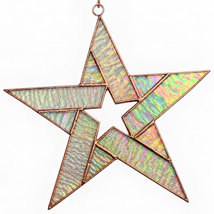 May include: A five-pointed star ornament constructed from iridescent, textured glass panels held together by copper-colored metal solder lines. The star features a hollow center and a small metal ring at the top for hanging, displaying a shimmering rainbow effect.