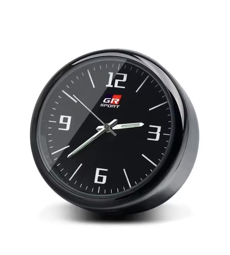 K&ouml;nnte beinhalten: Eine schwarze analoge Uhr mit wei&szlig;en Ziffern und Zeigern. Das Zifferblatt zeigt den Text "GR SPORT" und die Zahlen 12, 3, 6 und 9. Die Uhr hat eine gl&auml;nzend schwarze L&uuml;nette und einen wei&szlig;en Hintergrund.