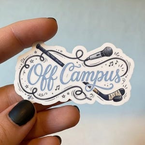 May include: A die-cut sticker featuring the text Off Campus in light blue cursive script. The design includes a black hockey stick, a hockey puck, and a microphone connected by swirling black lines, accented with small stars and musical notes.