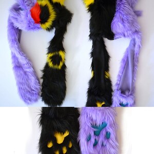 May include: Purple and black furry hat with a yellow and black striped tail. The hat has a long tail that can be worn as a scarf. The hat also has a pair of matching paw-shaped hand warmers.