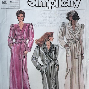 May include: A sewing pattern for a long robe with a sash and a shawl collar. The pattern includes three different views: a pink robe, a gray robe with a tassel, and a white robe with a floral design. The pattern is from Simplicity and is for sizes 6-14.