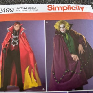 May include: Simplicity pattern 2499 featuring costume designs. One design shows a red cape with yellow flame accents, the other a purple cape with green bead trim. The pattern includes sizes AA XS, S, and M.