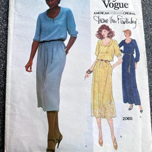 May include: Vintage Very Easy Vogue sewing pattern featuring a woman in a light blue dress with a matching skirt. The pattern includes illustrations of other dress designs. The designer's signature is visible.
