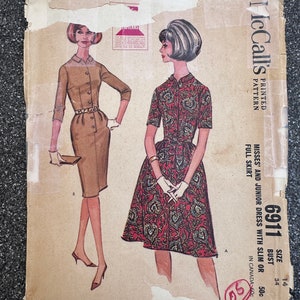 May include: Vintage McCall's sewing pattern for a dress, size 14 bust, 34. The pattern shows two women wearing the dress, one in a solid brown color and the other in a floral print. The pattern is labeled "6911" and is for misses' and junior sizes.