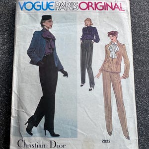 以下が含まれることがあります： クリスチャン・ディオールのデザインが特徴の、ヴィンテージVogue Paris Originalの裁縫パターン。表紙には、ブレザー、パンツ、スーツなど、女性ファッションのイラストが描かれています。パターン番号は2022です。