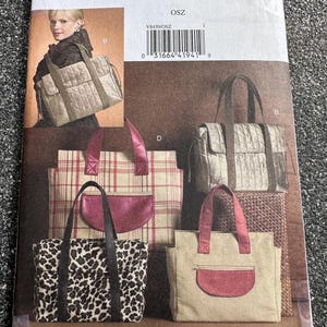May include: Vogue Accessories pattern V8439 featuring tote bags. The pattern includes various bag designs, including a leopard print, plaid, and solid-colored options. The bags have different handle styles and pocket details.