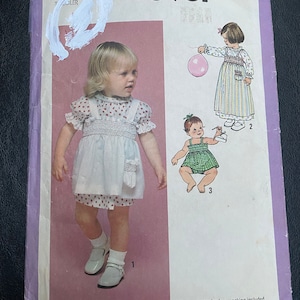 May include: Simplicity sewing pattern number 8951 for a toddler's dress with smocking. The pattern includes instructions for three different styles: a white dress with red polka dots, a green and white gingham dress, and a striped dress with a pocket.