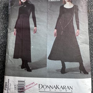 May include: Vogue Patterns sewing pattern featuring two long black dresses. The pattern is designed by Donna Karan New York. The package includes the Vogue Patterns logo and the text "Vogue American Designer".